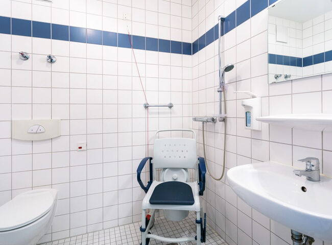 Badezimmer mit Toilette, Toilettenstuhl und Waschbecken