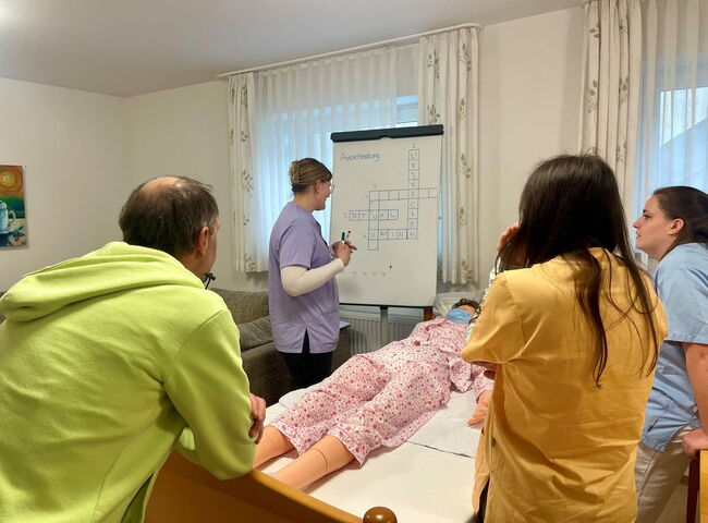 Azubis üben an einer Pflegepuppe