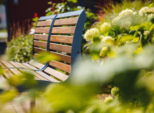 Eine gemütliche Sitzbank vor Sträuchern