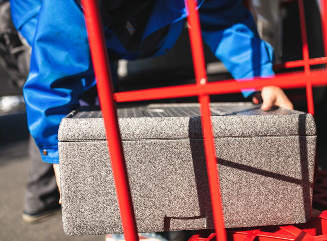 Eine Mitarbeiterin stapelt Wärmebehälter auf den Transportwagen