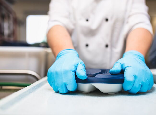 Ein Teller wird mit einem Silikondeckel verschlossen