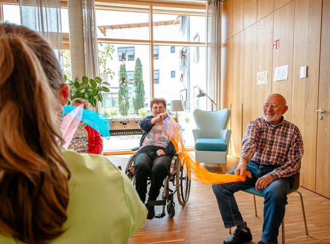 Eine Mitarbeiterin beschäftigt die Besucher mit einem therapeutischen Tücherspiel