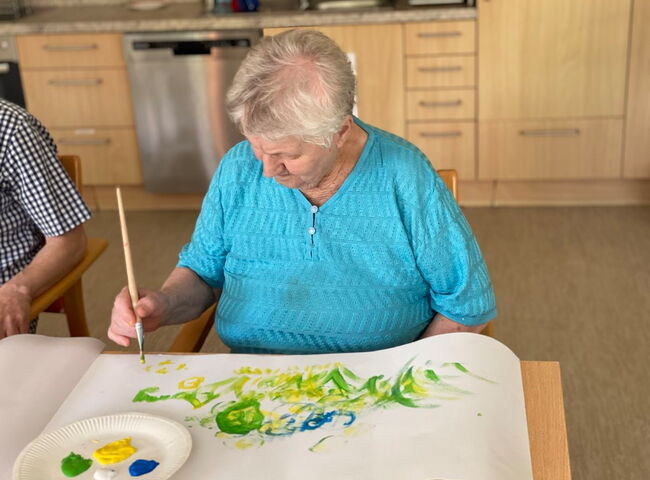 Eine Seniorin malt ein Bild mit einem Pinsel