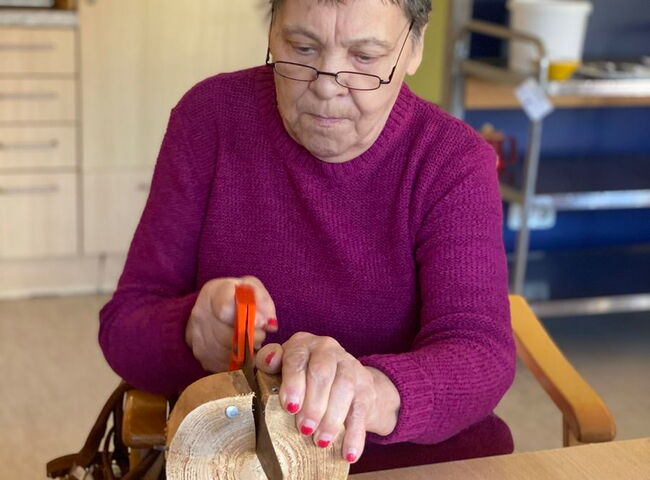 Eine Bewohnerin bei Sägearbeiten an einem Holzstück