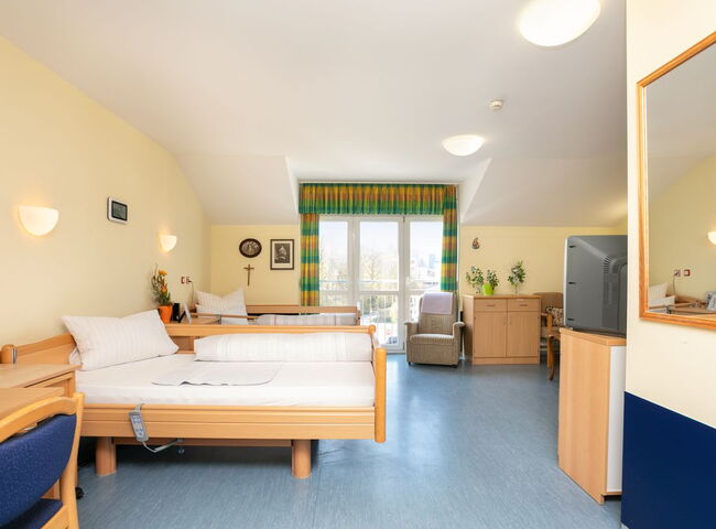 Blick in ein bewohntes Zimmer mit Betten, Couch und Möbeln