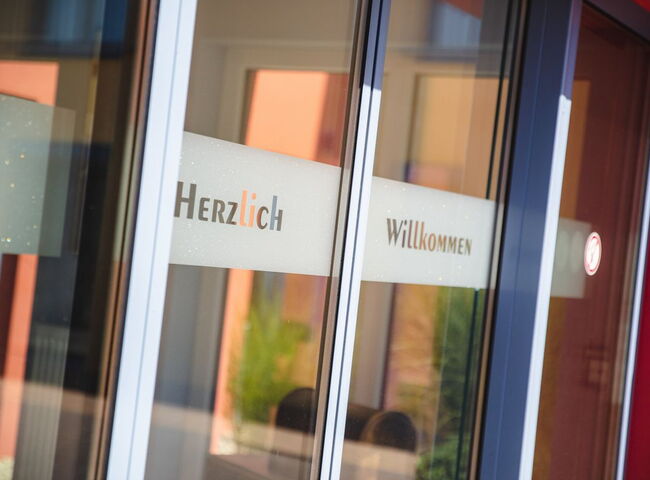 Tür Haupteingang mit Aufschrift Herzlich Willkommen