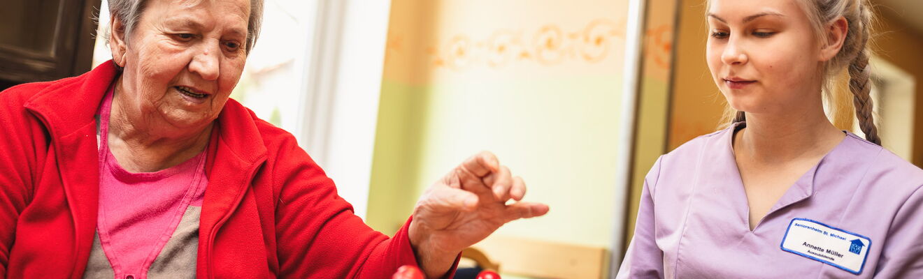 Eine Auszubildende spielt mit einer Bewohnerin Mensch Ärgere Dich Nicht