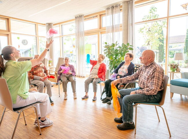 Eine Mitarbeiterin beschäftigt die Besucher mit einem therapeutischen Tücherspiel