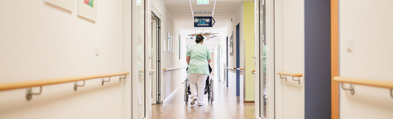 Pflegepersonal schiebt Rollstuhl