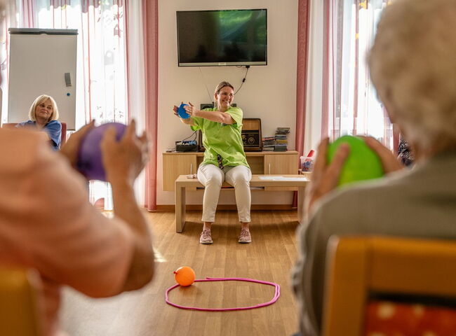 Eine Mitarbeiterin spielt mit den Gästen ein Luftballonspiel