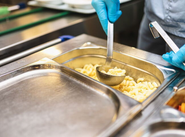 Nudeln werden mit der Kelle aus dem Thermowagen gefasst